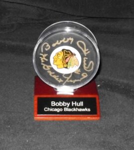 Bobby Hull signed Blackhawks puck with 'HOF 1983' inscription in display case with nameplate and certificate of authenticity